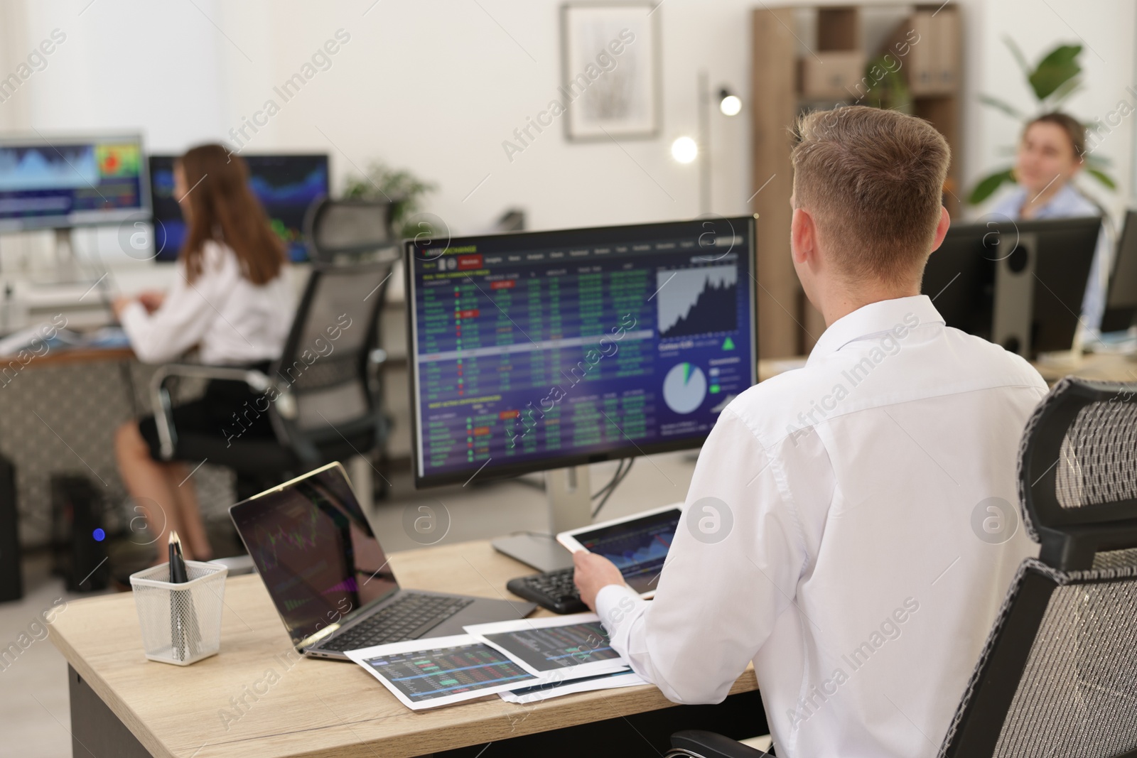 Photo of Stock exchange. Man working at desk in office, back view