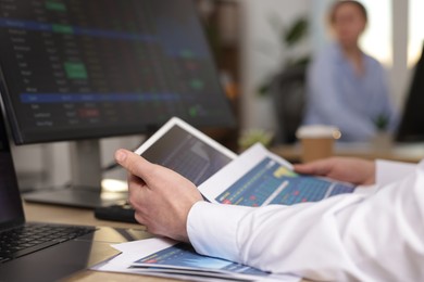 Photo of Stock exchange. Man working at desk in office, closeup