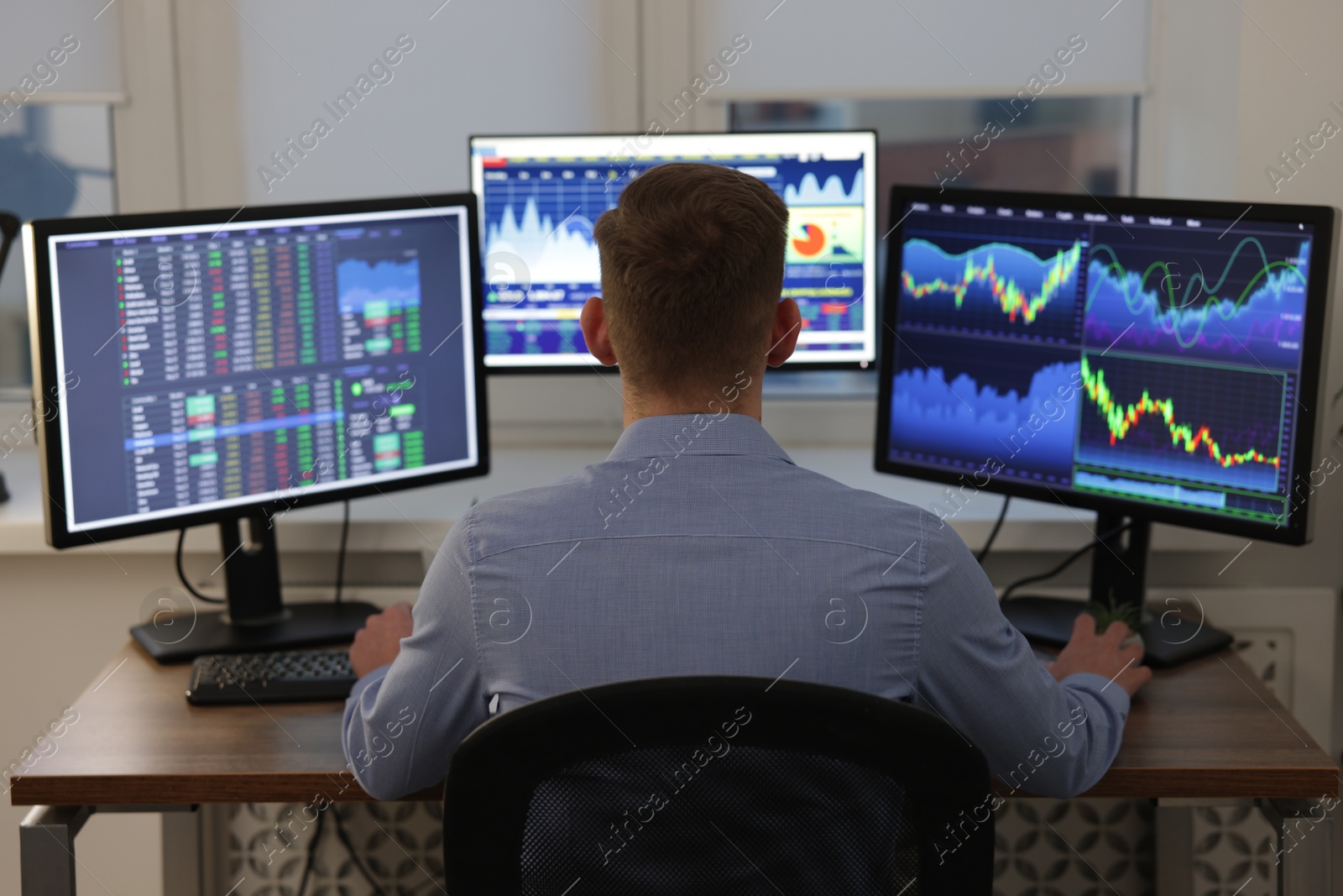 Photo of Stock exchange. Man working at desk in office, back view