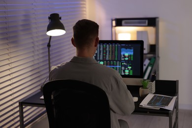 Photo of Stock exchange. Man working in office at night, back view