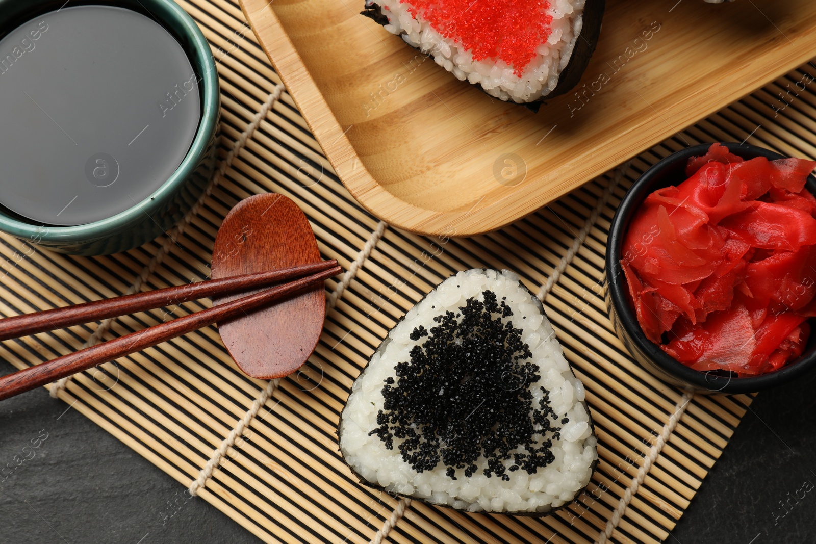 Photo of Tasty tobiko onigiri (Japanese rice balls) served on black table, flat lay