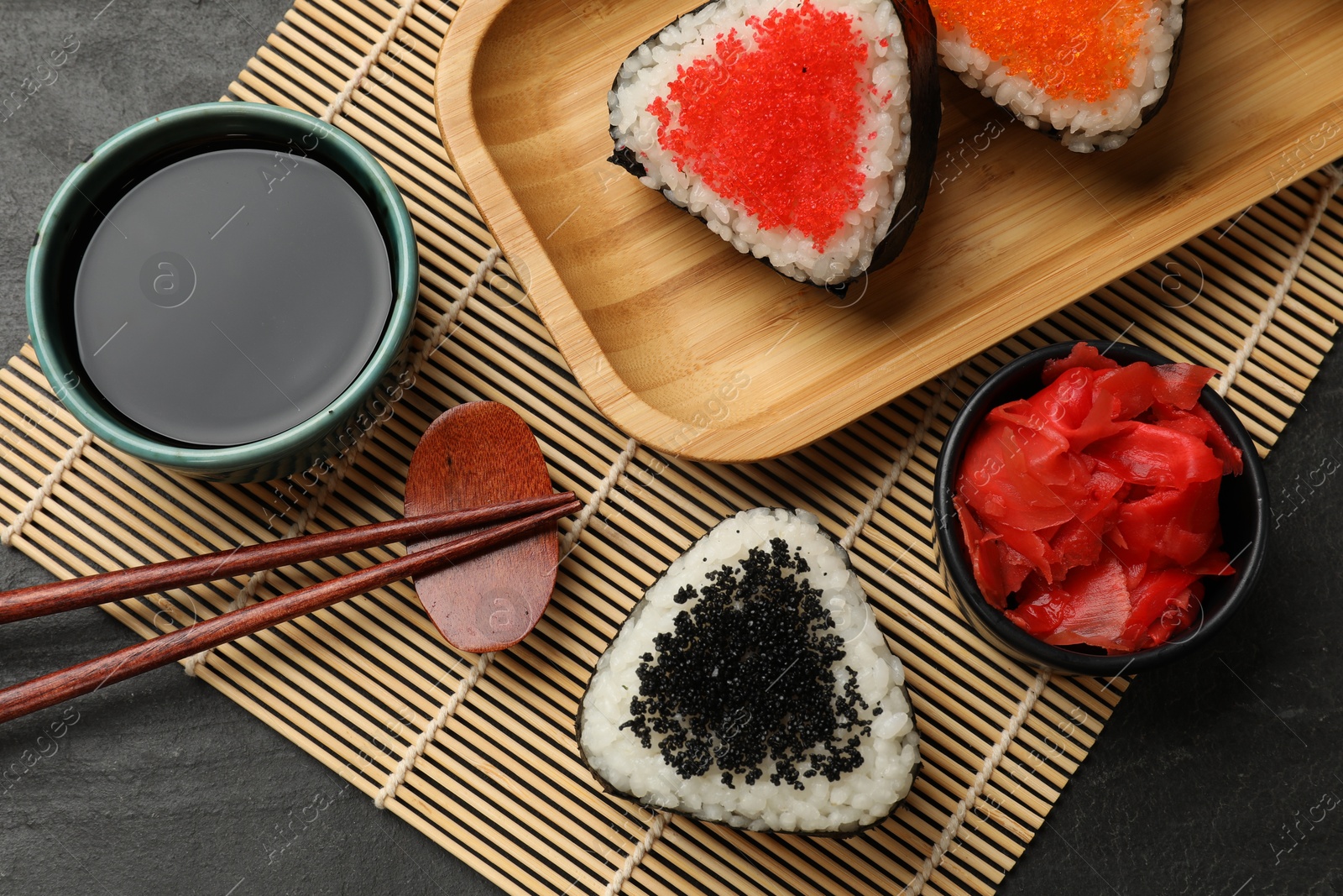 Photo of Tasty tobiko onigiri (Japanese rice balls) served on black table, flat lay