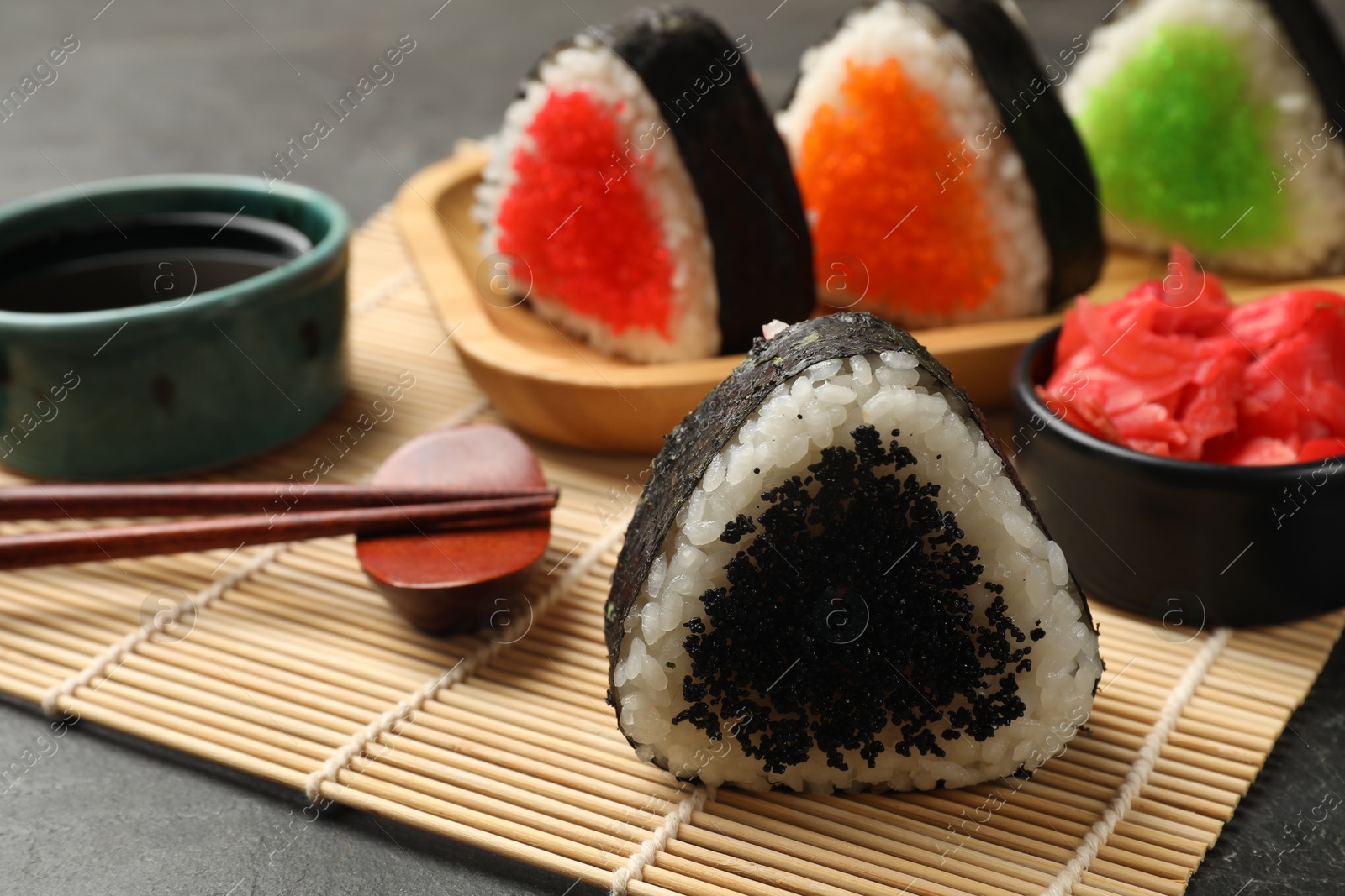 Photo of Tasty tobiko onigiri (Japanese rice balls) served on black table, closeup