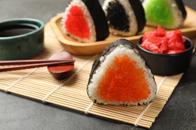 Photo of Tasty tobiko onigiri (Japanese rice balls) served on black table, closeup