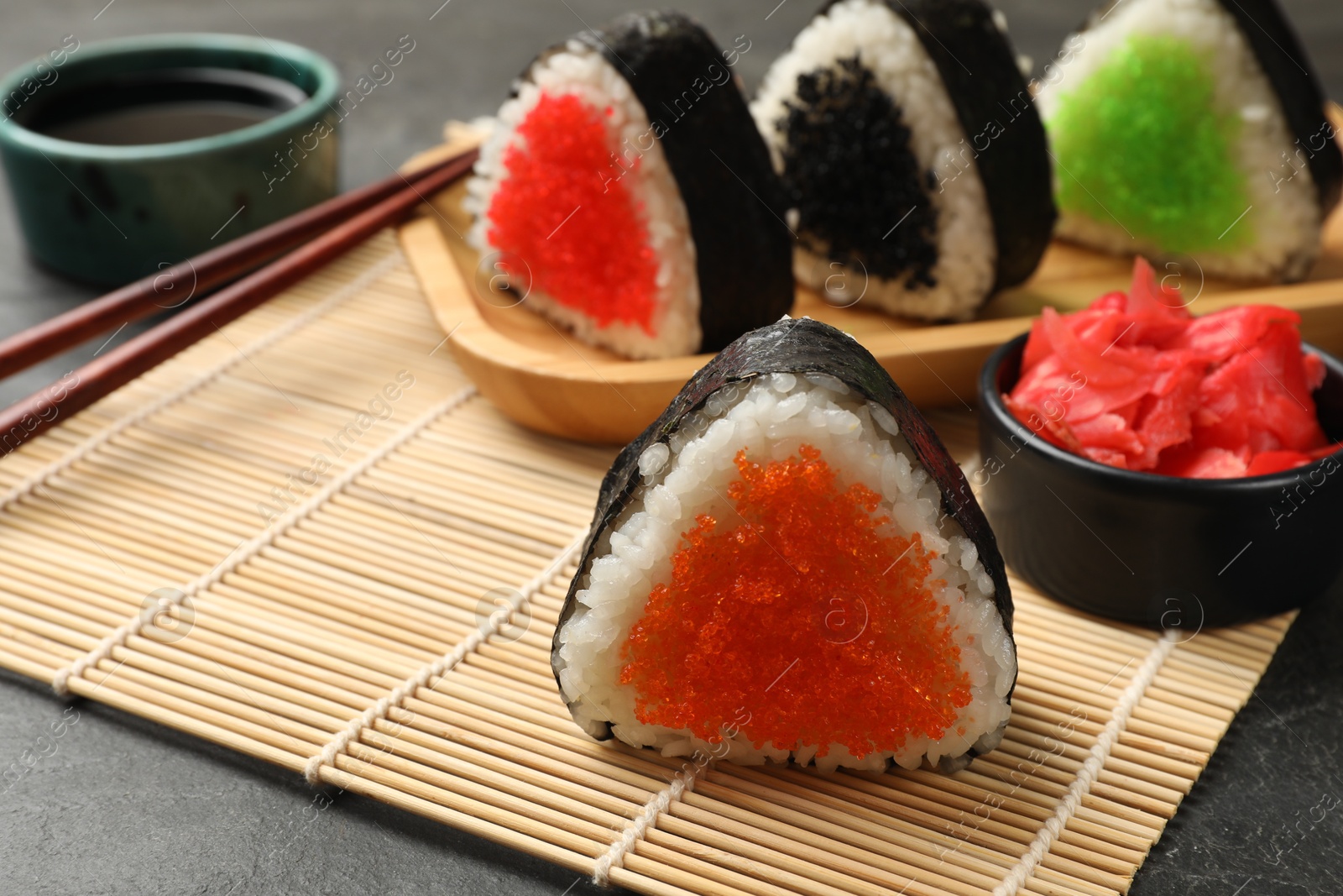 Photo of Tasty tobiko onigiri (Japanese rice balls) served on black table, closeup