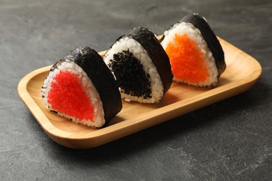 Photo of Tasty tobiko onigiri (Japanese rice balls) on black table, closeup