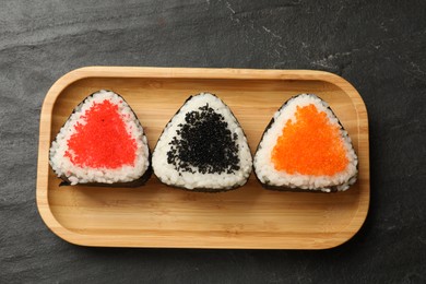 Photo of Tasty tobiko onigiri (Japanese rice balls) on black table, top view