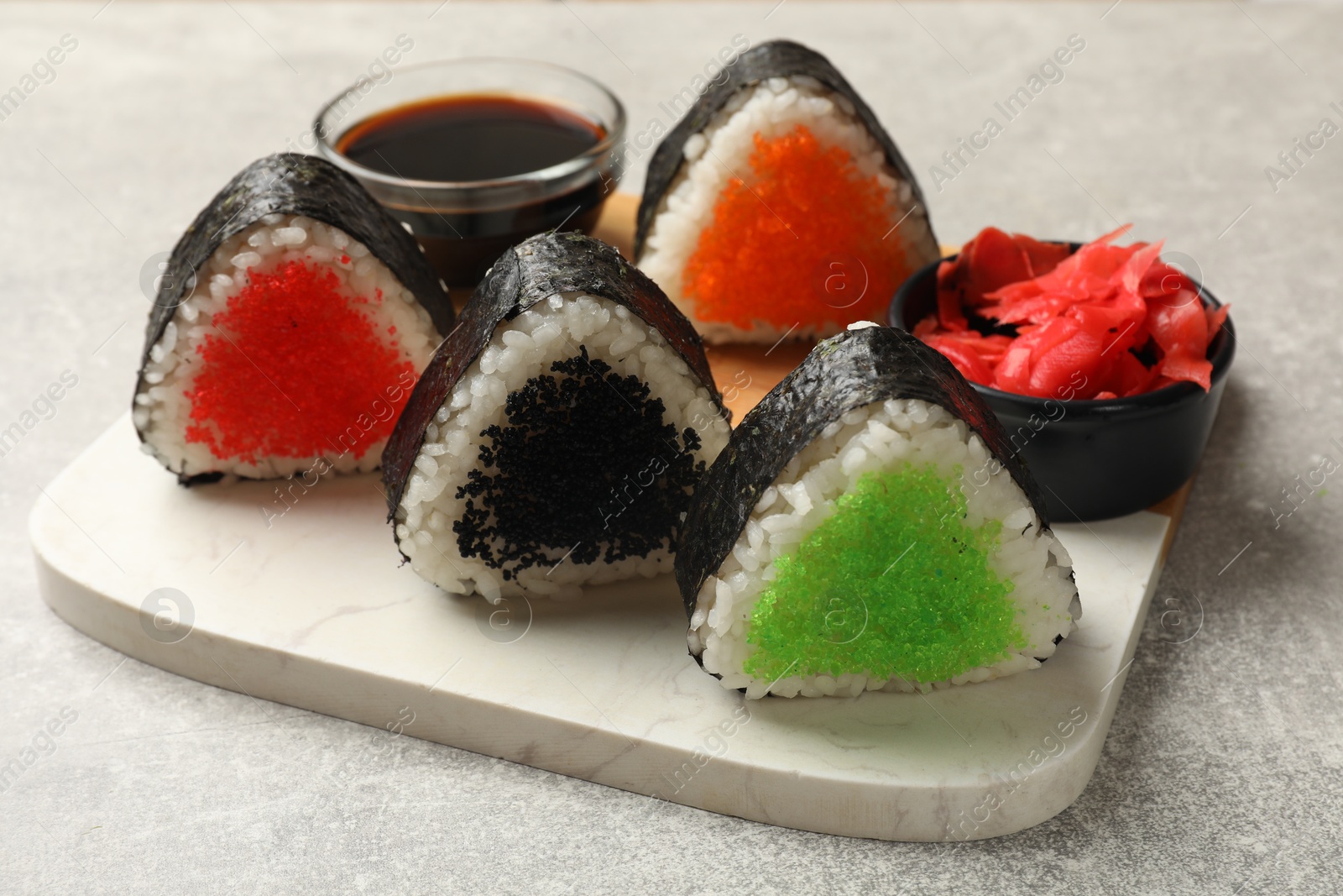 Photo of Tasty tobiko onigiri (Japanese rice balls) served on light grey table, closeup