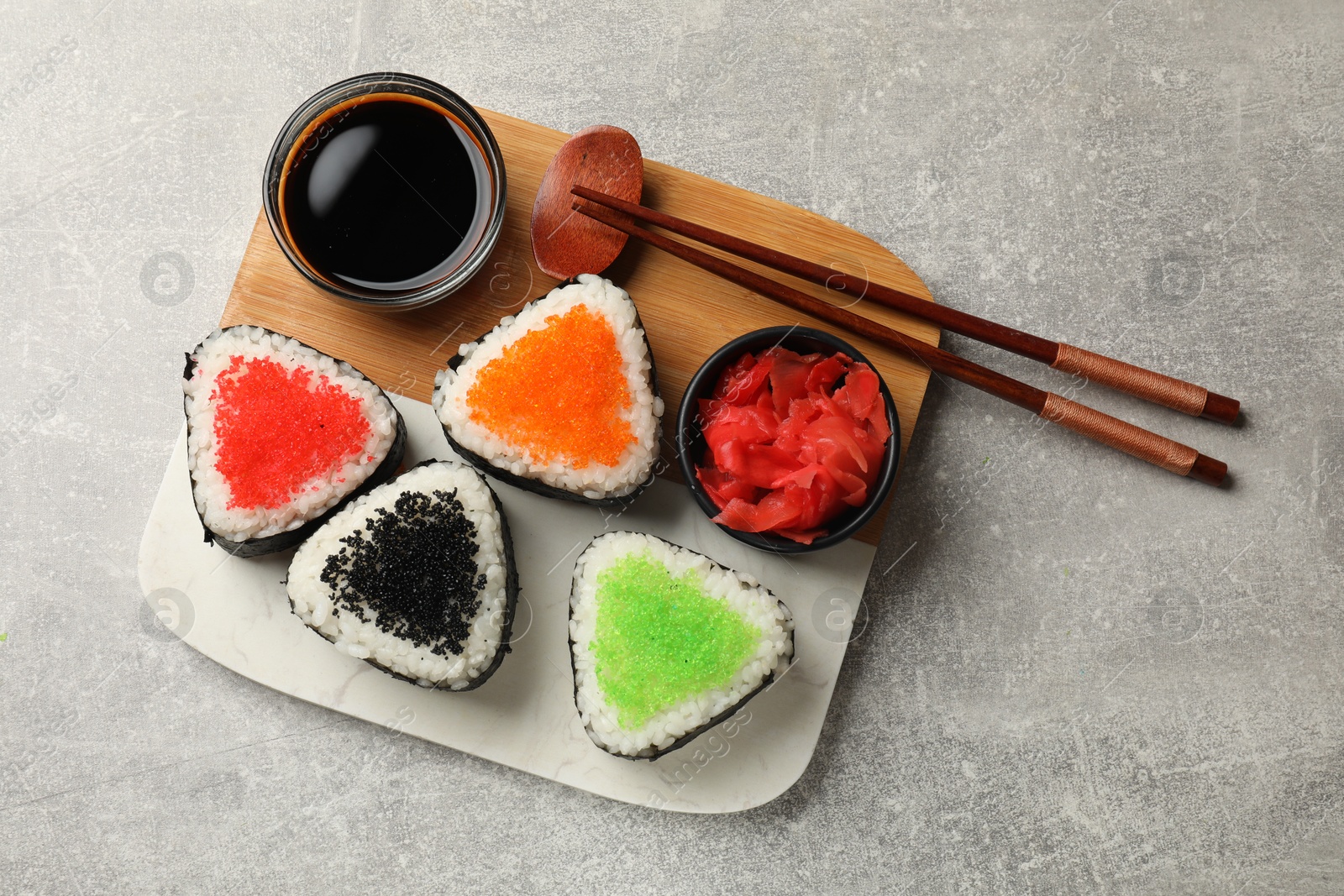 Photo of Tasty tobiko onigiri (Japanese rice balls) served on light grey table, top view