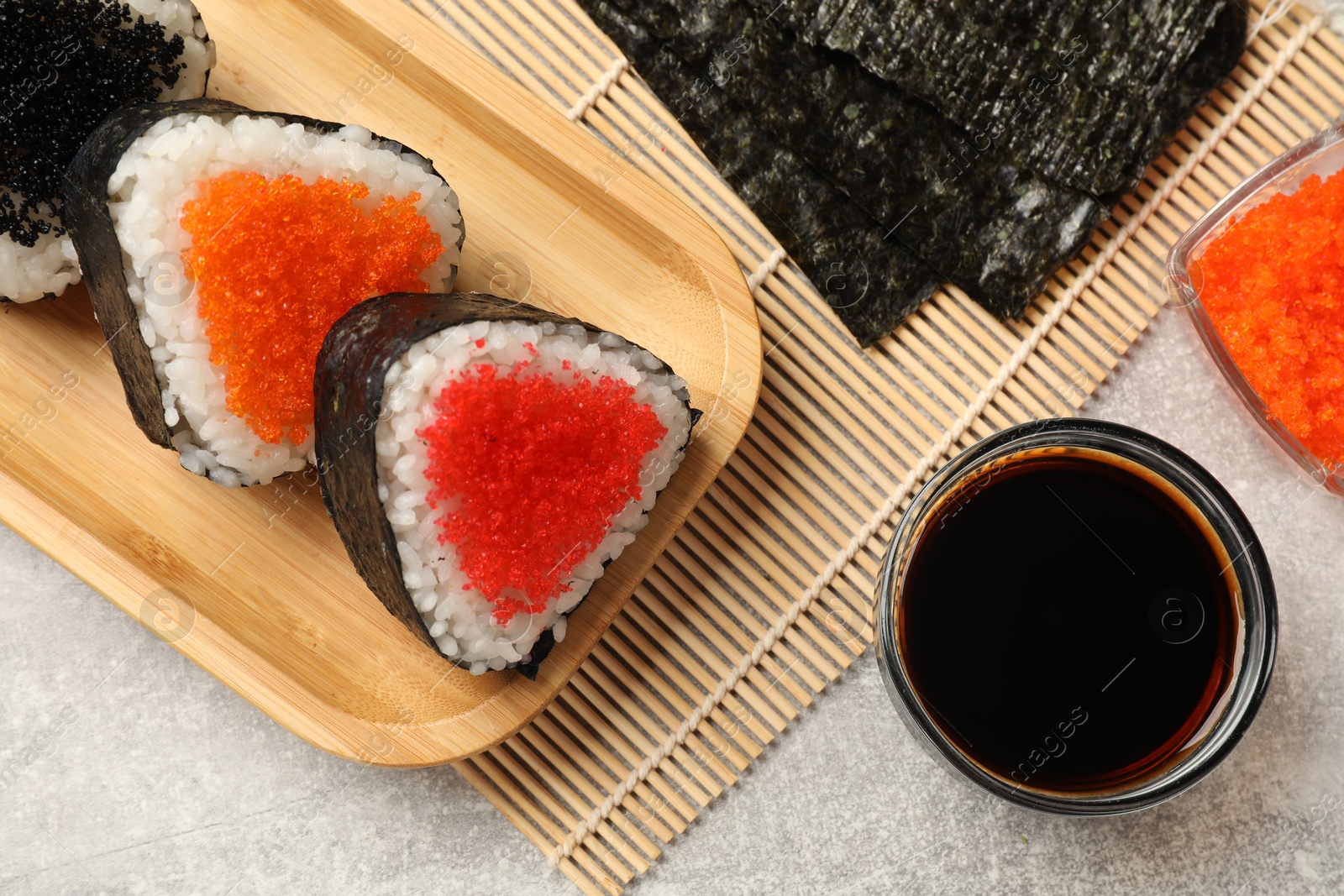 Photo of Tasty tobiko onigiri (Japanese rice balls) served on light grey table, flat lay