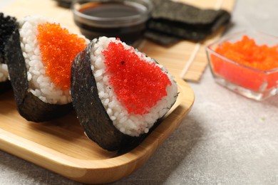 Photo of Tasty tobiko onigiri (Japanese rice balls) served on light grey table, closeup. Space for text