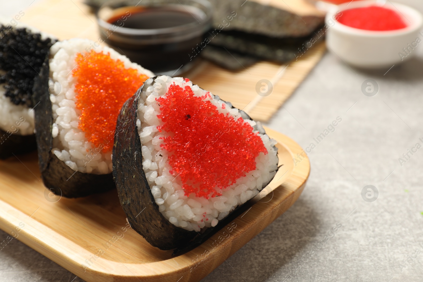 Photo of Tasty tobiko onigiri (Japanese rice balls) served on light grey table, closeup. Space for text