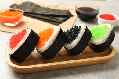 Photo of Tasty tobiko onigiri (Japanese rice balls) served on light grey table, closeup