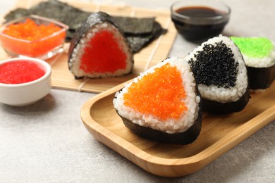 Photo of Tasty tobiko onigiri (Japanese rice balls) served on light grey table, closeup