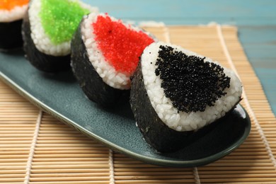 Photo of Tasty tobiko onigiri (Japanese rice balls) on table, closeup