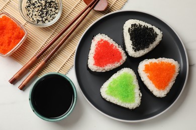 Photo of Tasty tobiko onigiri (Japanese rice balls) served on white marble table, flat lay