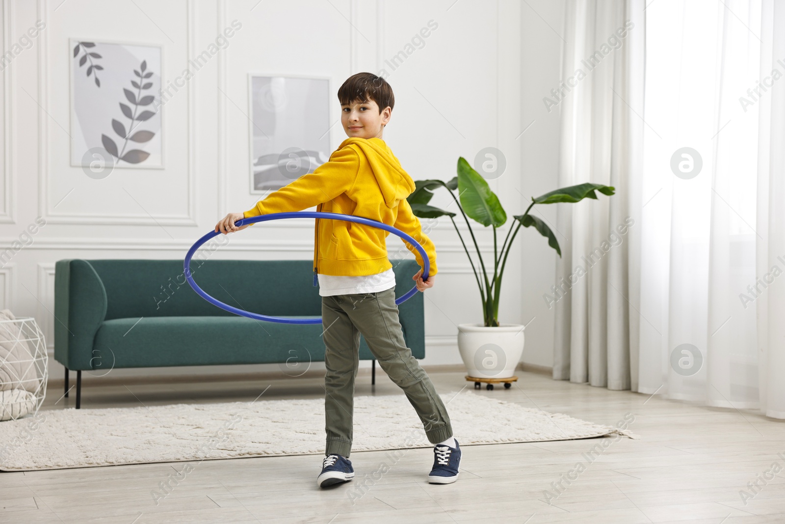 Photo of Boy exercising with hula hoop at home