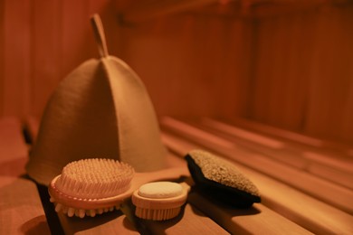 Photo of Bath accessories and felt wool hat on bench in sauna. Space for text