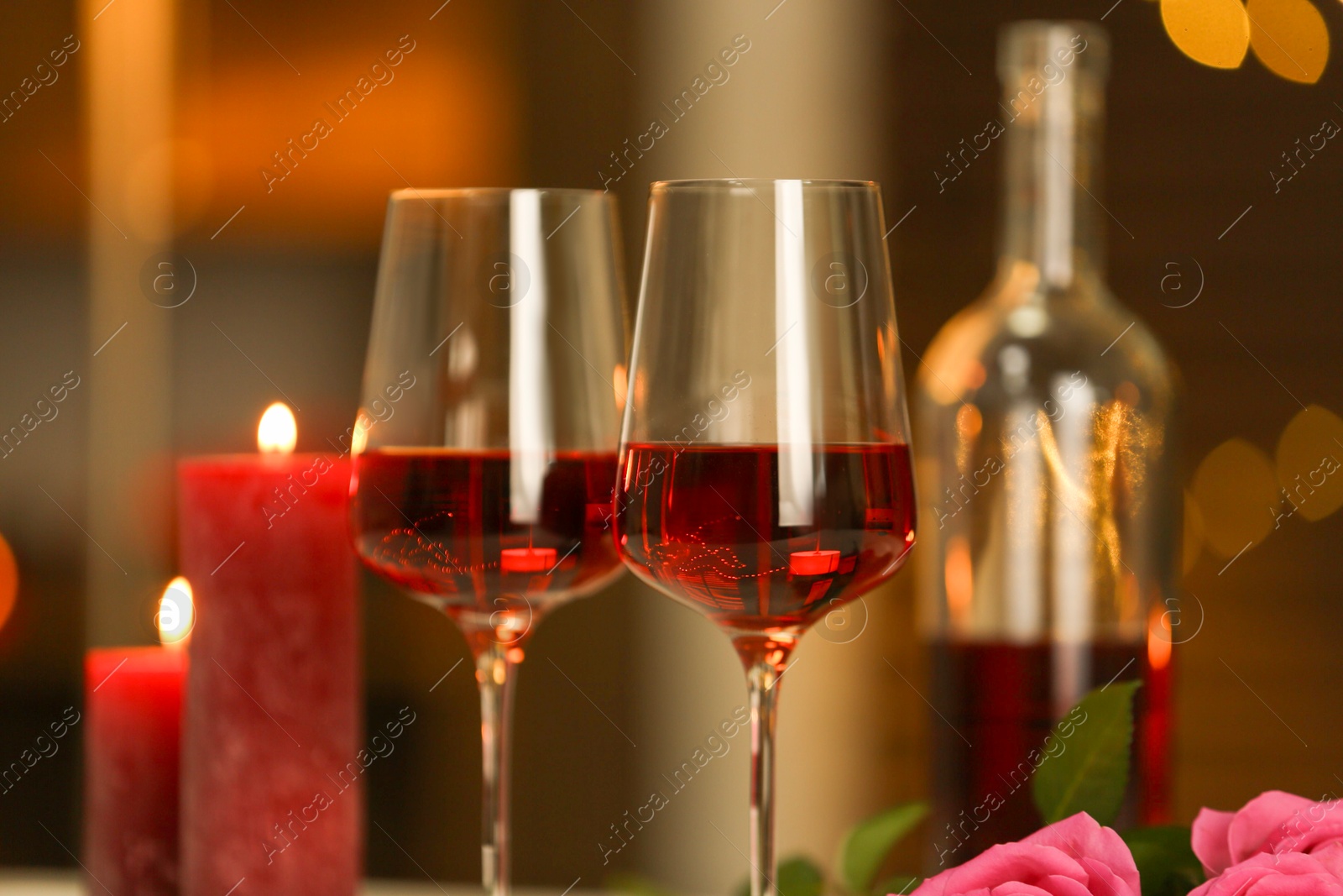 Photo of Glasses of red wine against blurred background, closeup. Romantic dinner