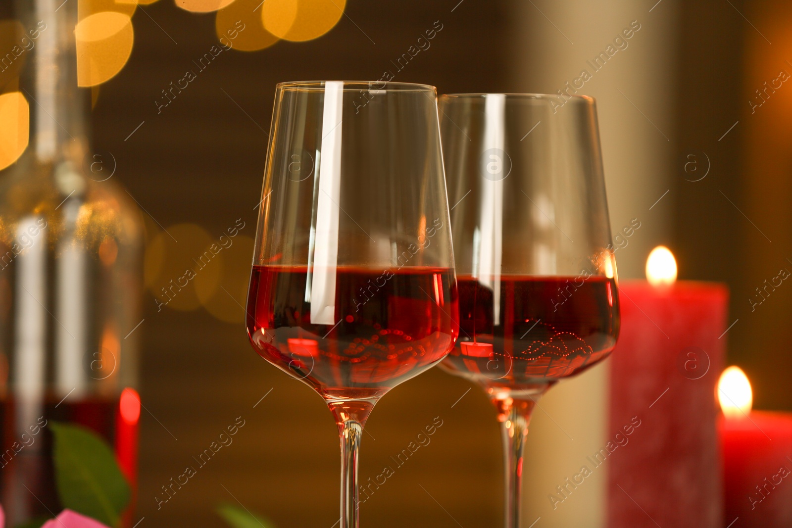 Photo of Glasses of red wine against blurred background, closeup. Romantic dinner