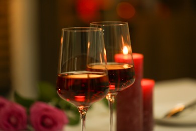 Photo of Glasses of red wine against blurred background, closeup. Romantic dinner