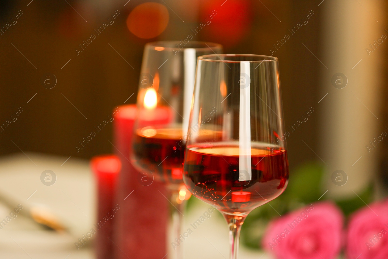 Photo of Romantic dinner. Glasses of red wine against blurred background, closeup. Space for text