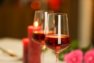 Photo of Romantic dinner. Glasses of red wine against blurred background, closeup. Space for text