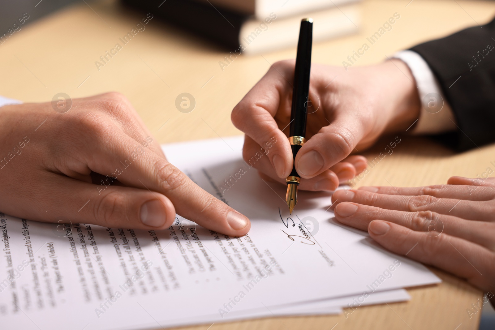 Photo of Man pointing at document and woman putting signature at table, closeup