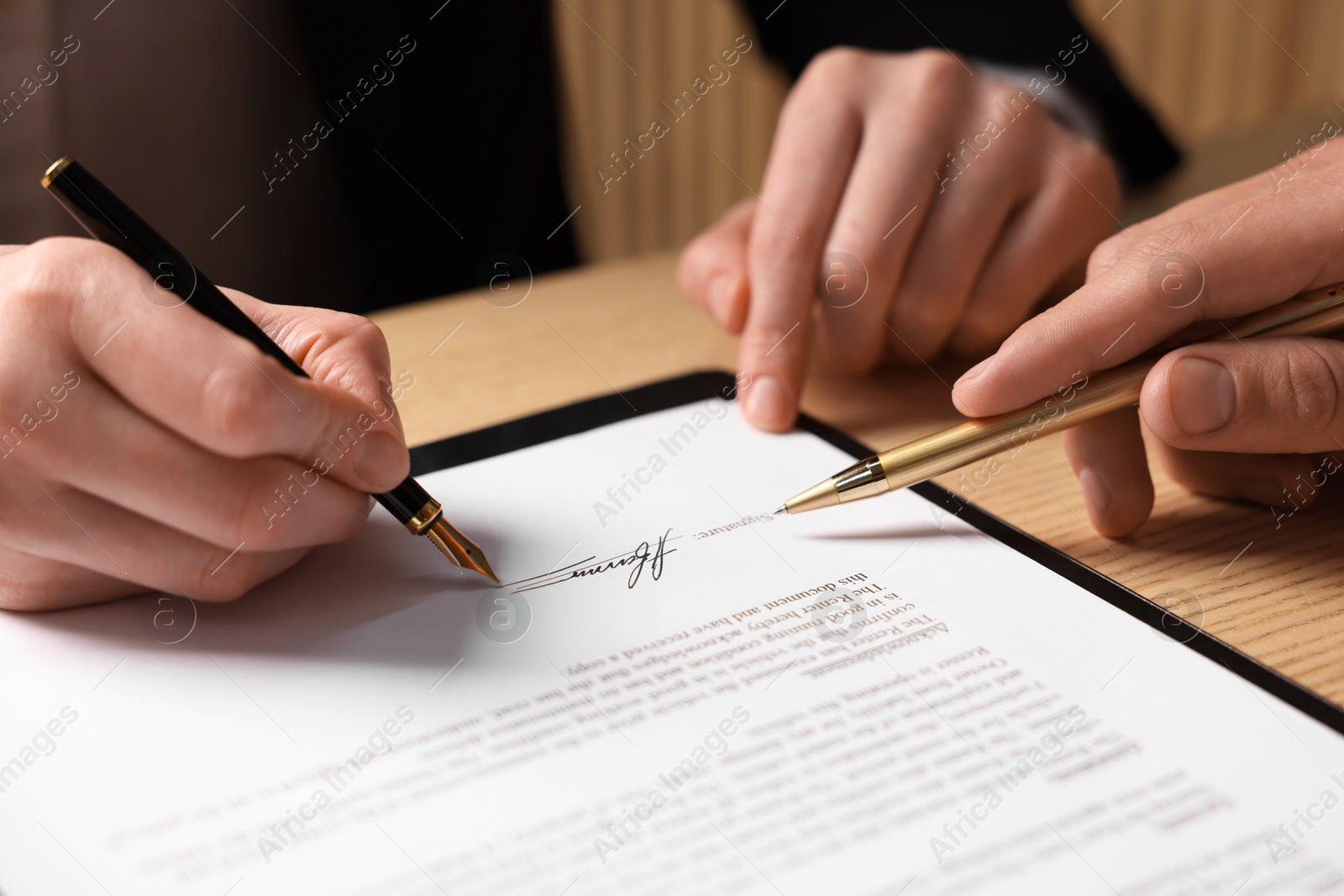 Photo of Man pointing at document and woman putting signature at table, closeup