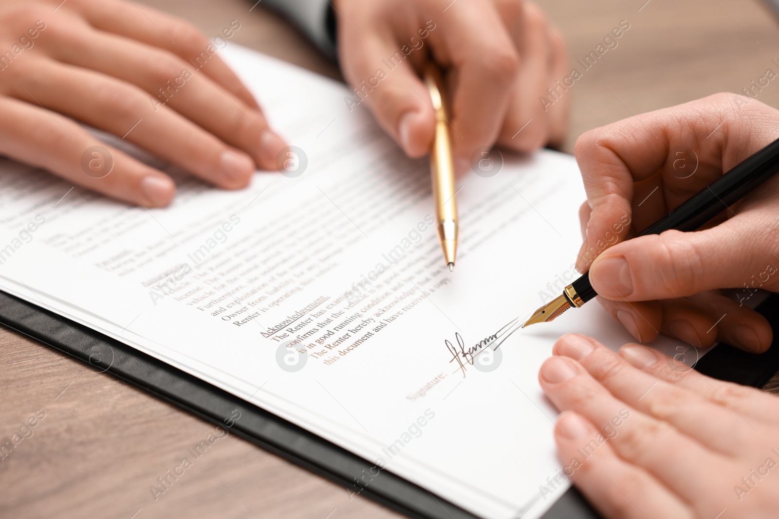 Photo of Man pointing at document and woman putting signature at table, closeup