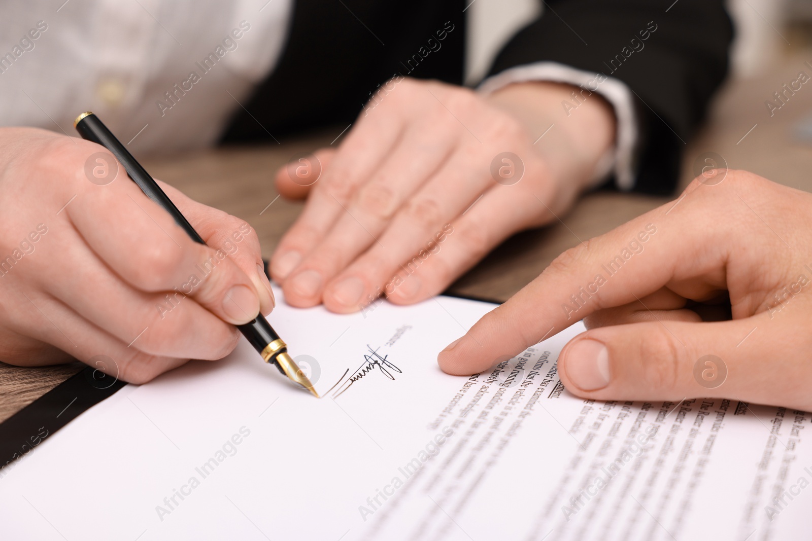 Photo of Man pointing at document and woman putting signature at table, closeup