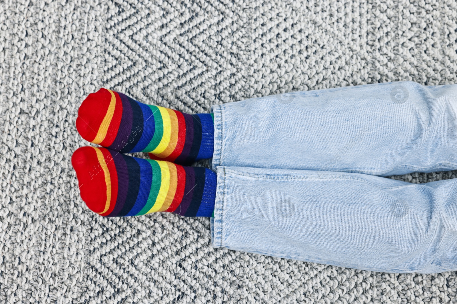 Photo of Man wearing socks in colors of LGBT flag on floor indoors, top view