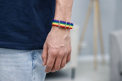 Photo of Man with bracelet in colors of LGBT flag indoors, closeup. Space for text