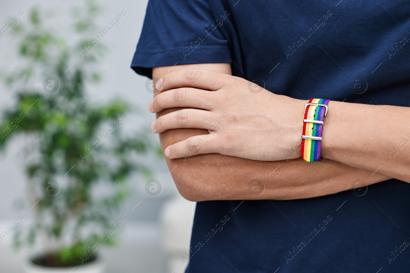 Photo of Man with bracelet in colors of LGBT flag indoors, closeup. Space for text