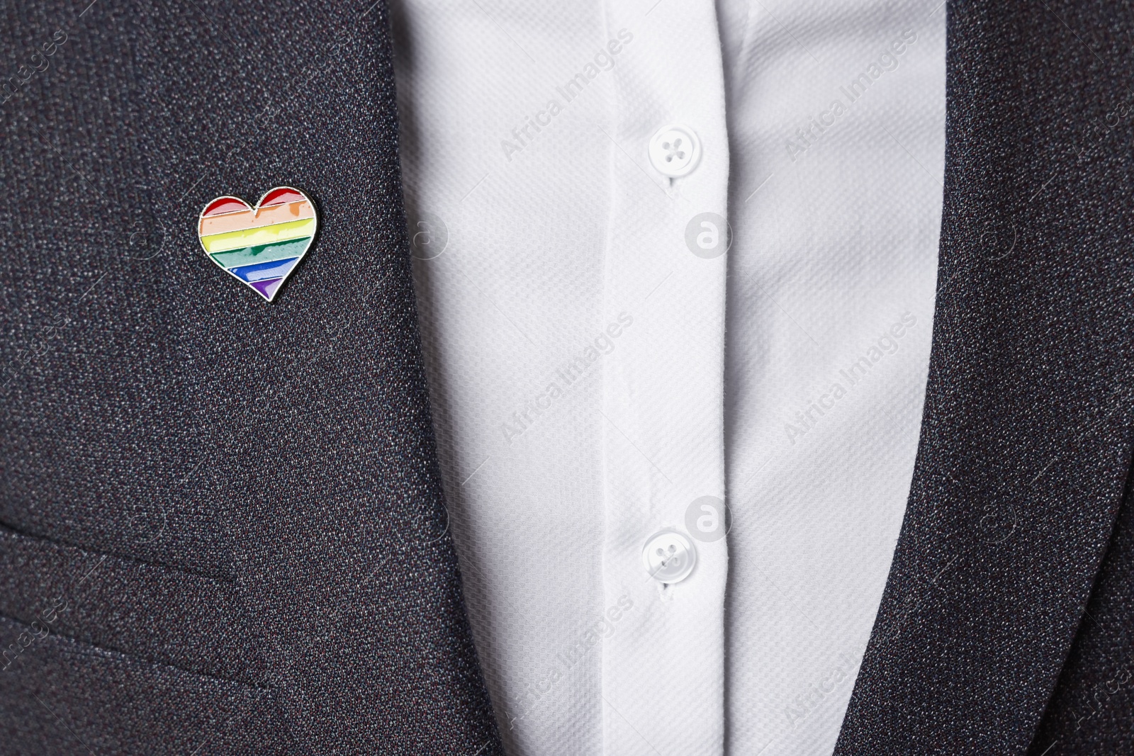 Photo of Man with heart shaped pin in colors of LGBT flag, closeup