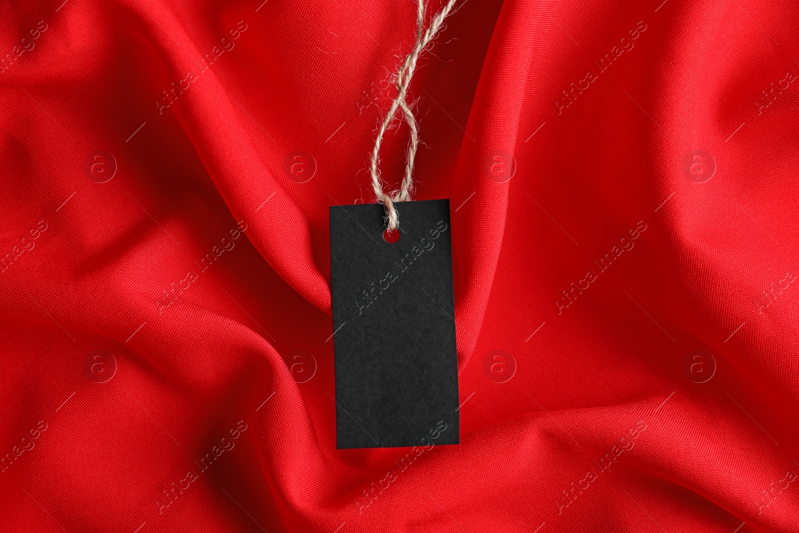 Blank tag with string on red fabric, top view Photo of Blank tag with string on red fabric, top view