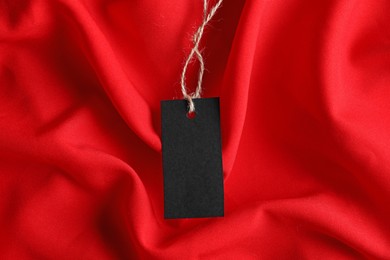 Photo of Blank tag with string on red fabric, top view