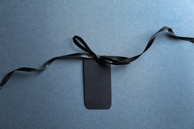 Photo of Blank tag with ribbon bow on grey background, top view