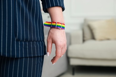 Photo of Woman wearing wristband in LGBT colors indoors, closeup. Space for text