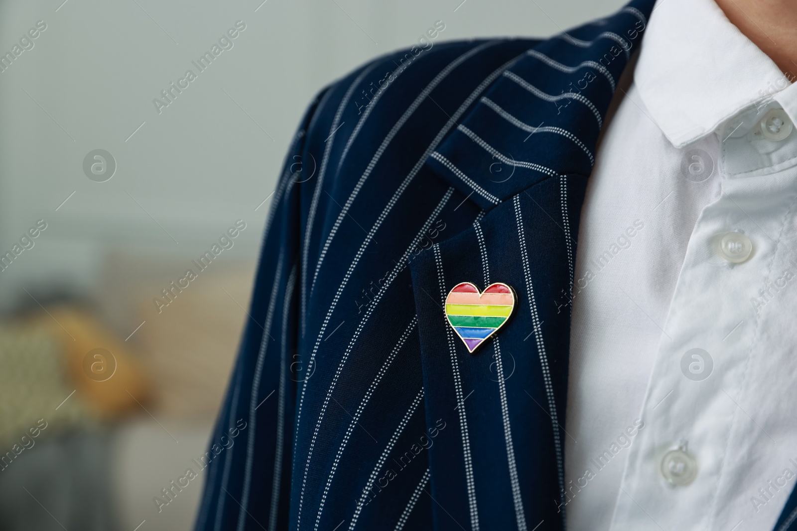 Photo of Woman with heart shaped pin in LGBT colors indoors, closeup