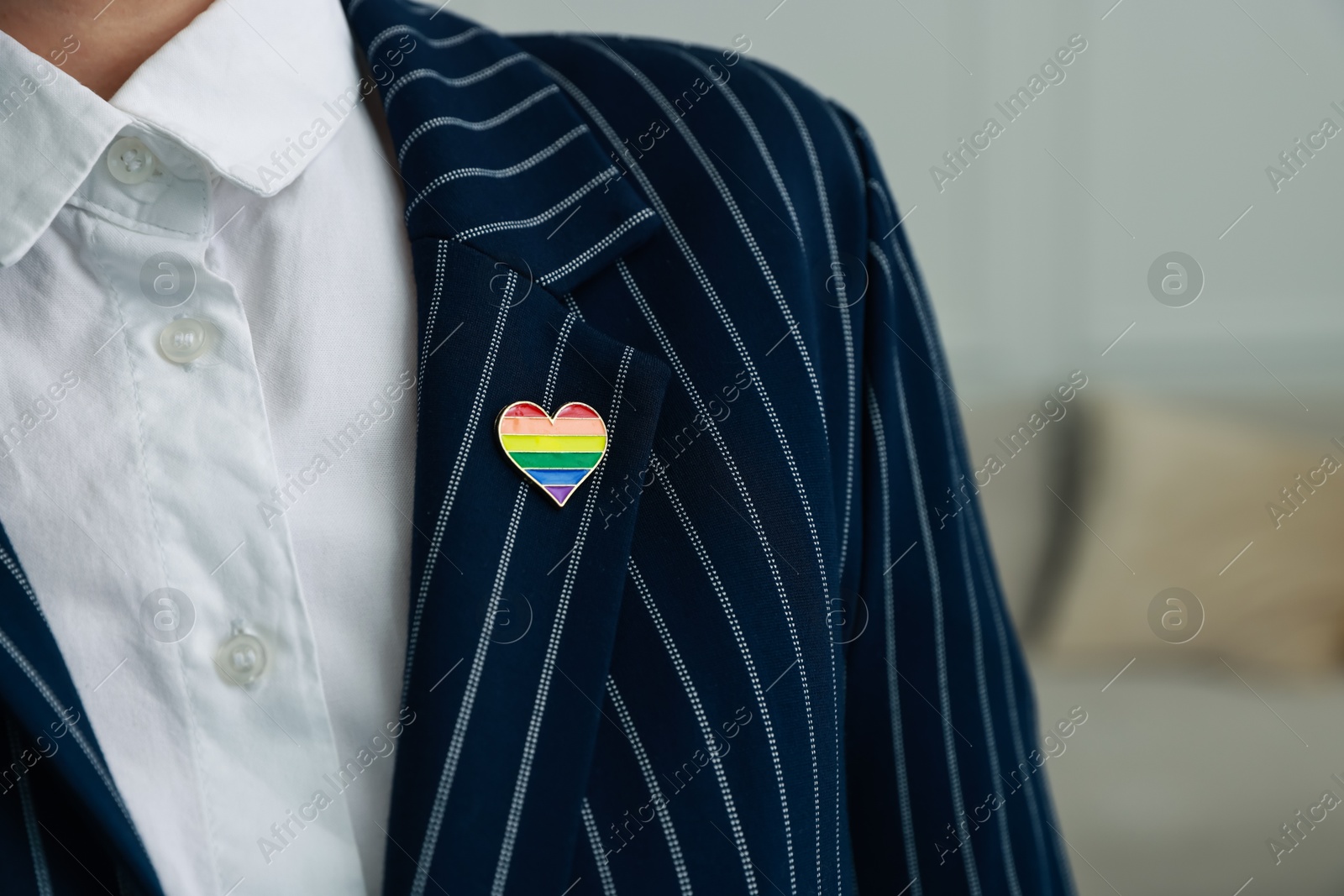 Photo of Woman with heart shaped pin in LGBT colors indoors, closeup