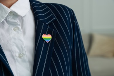 Photo of Woman with heart shaped pin in LGBT colors indoors, closeup