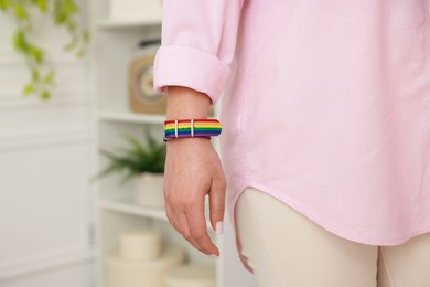 Photo of Woman wearing wristband in LGBT colors indoors, closeup. Space for text