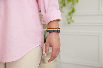 Photo of Woman wearing wristband in LGBT colors indoors, closeup. Space for text