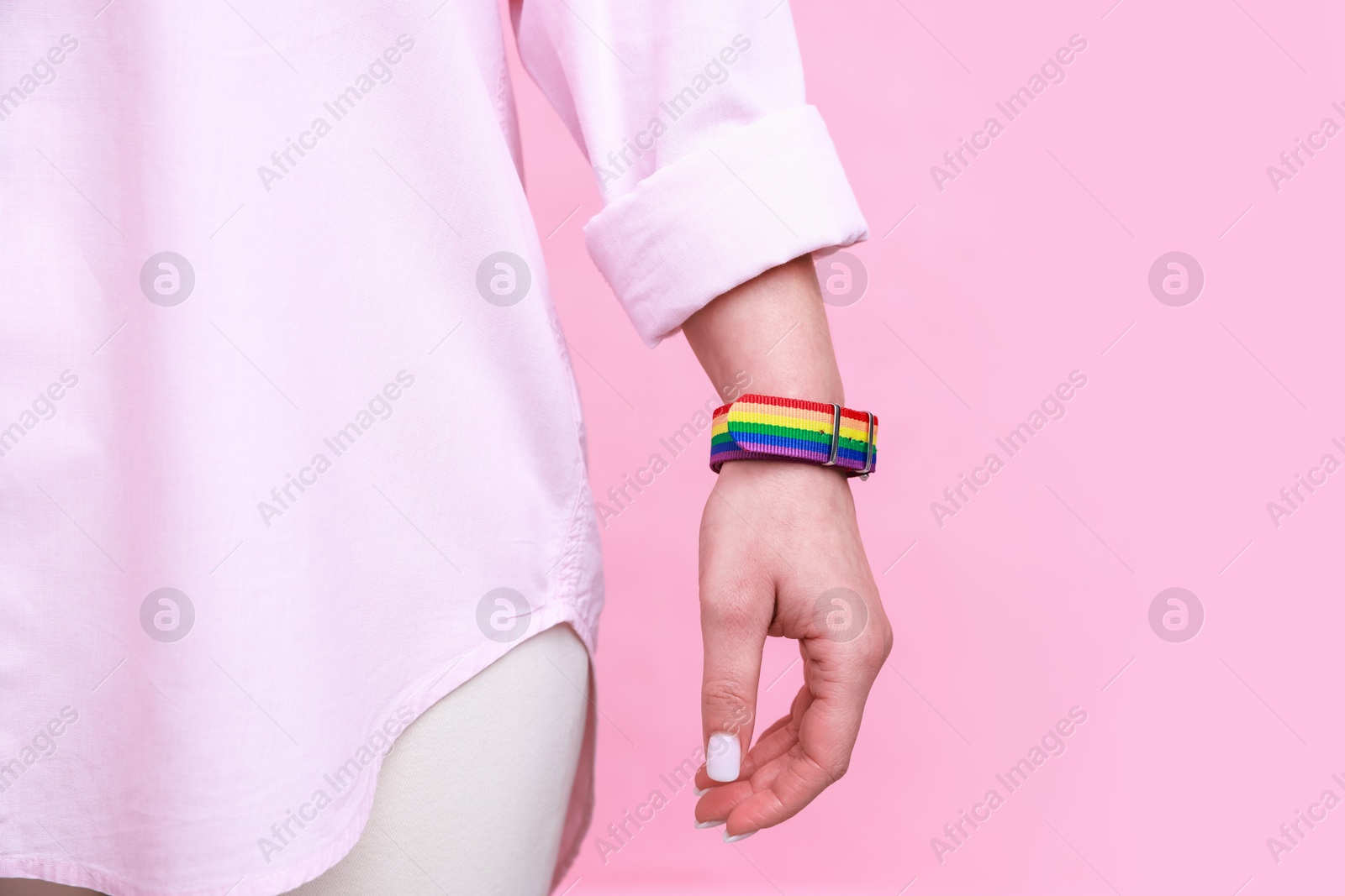 Photo of Woman wearing wristband in LGBT colors on pink background, closeup. Space for text