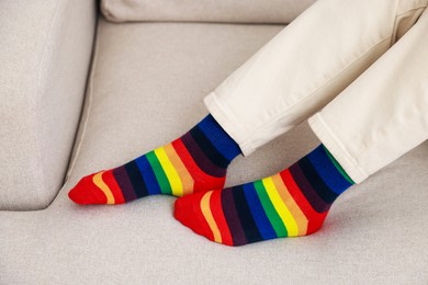 Photo of Woman wearing socks in LGBT colors on sofa indoors, closeup