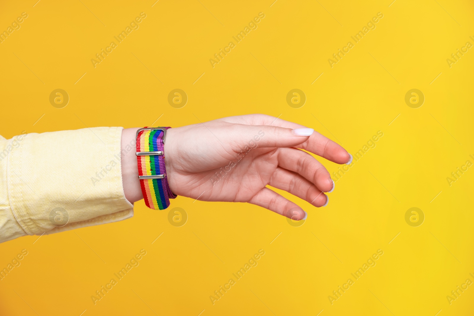 Photo of Woman wearing wristband in LGBT colors on orange background, closeup