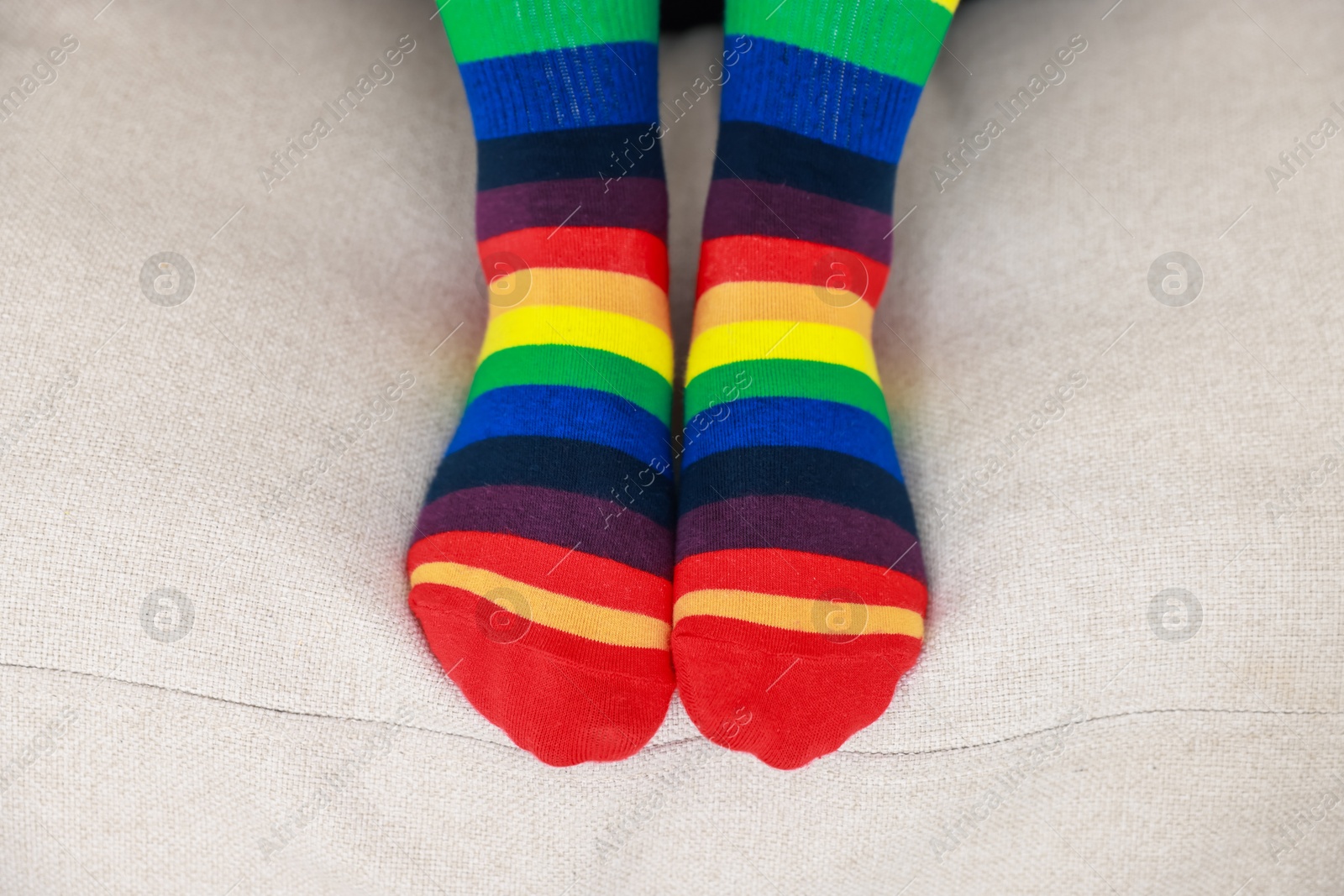 Photo of Woman wearing socks in LGBT colors on sofa indoors, closeup