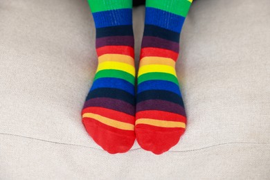 Photo of Woman wearing socks in LGBT colors on sofa indoors, closeup