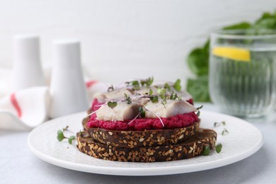 Tasty sandwiches with herring and horseradish sauce on light table, closeup